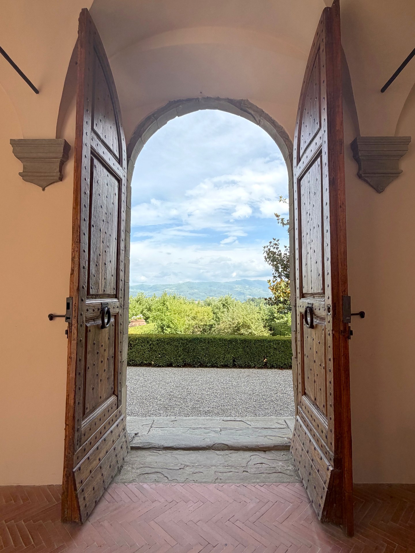 Historic wooden doors of Castello Vicchiomaggio opening onto the Tuscan landscape and Chianti hills