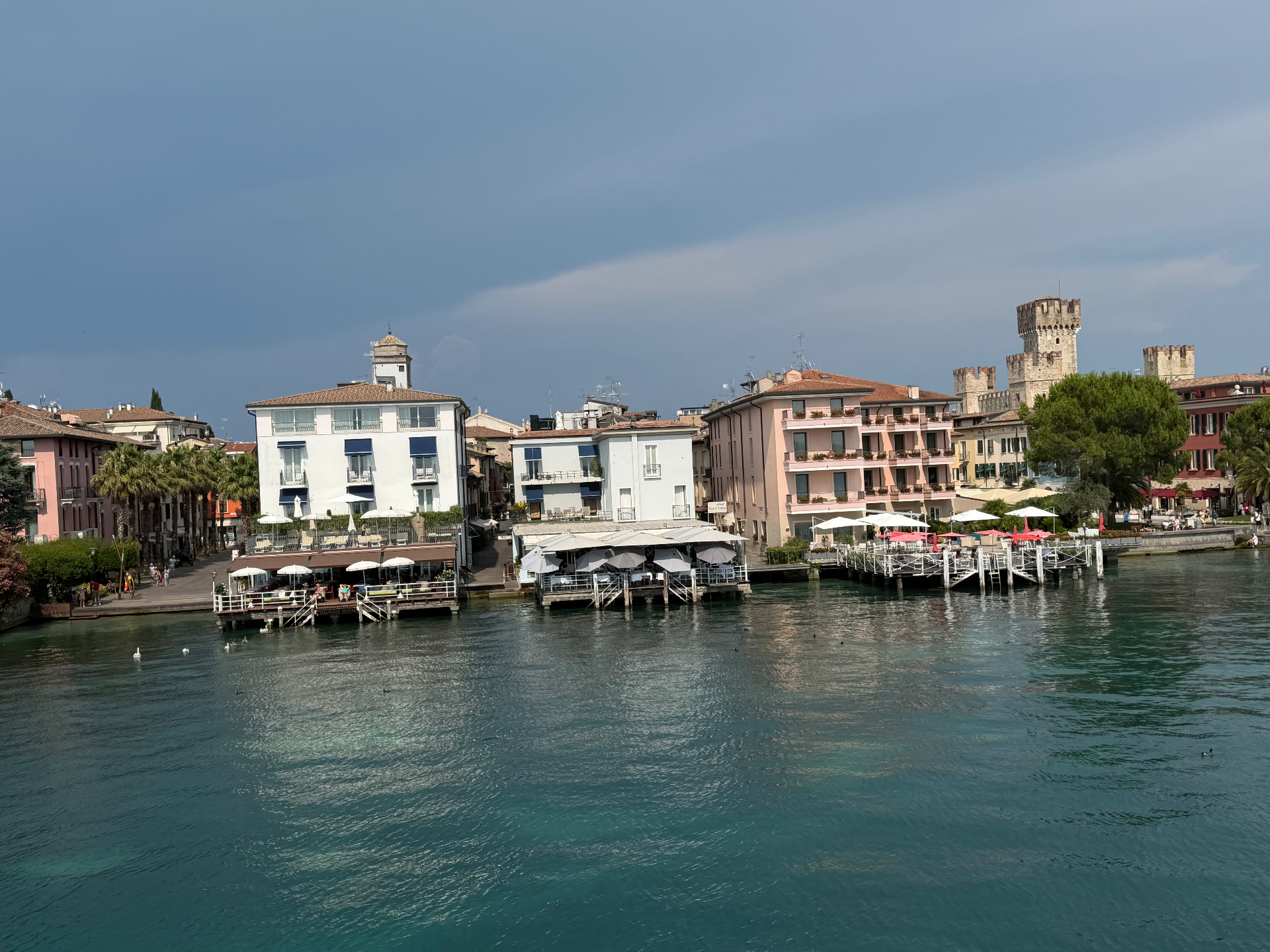 Historic pastel buildings and the Scaligero castle above the turquoise waters of Lake Garda in Sirmione
